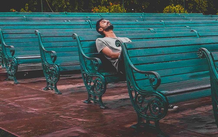 man sitting and closing eyes on teal bench